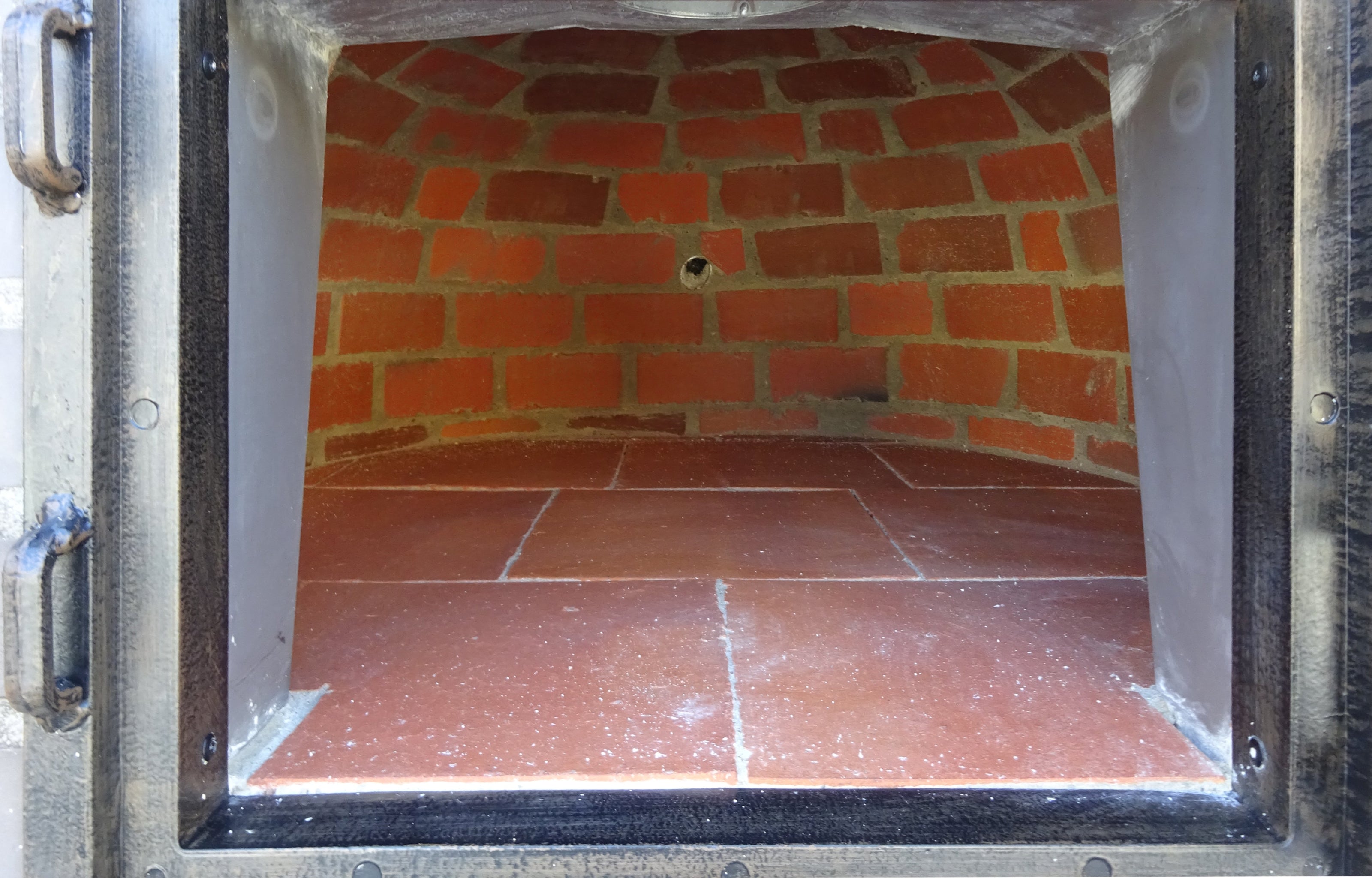 Internal view of a brick oven with a tiled floor
