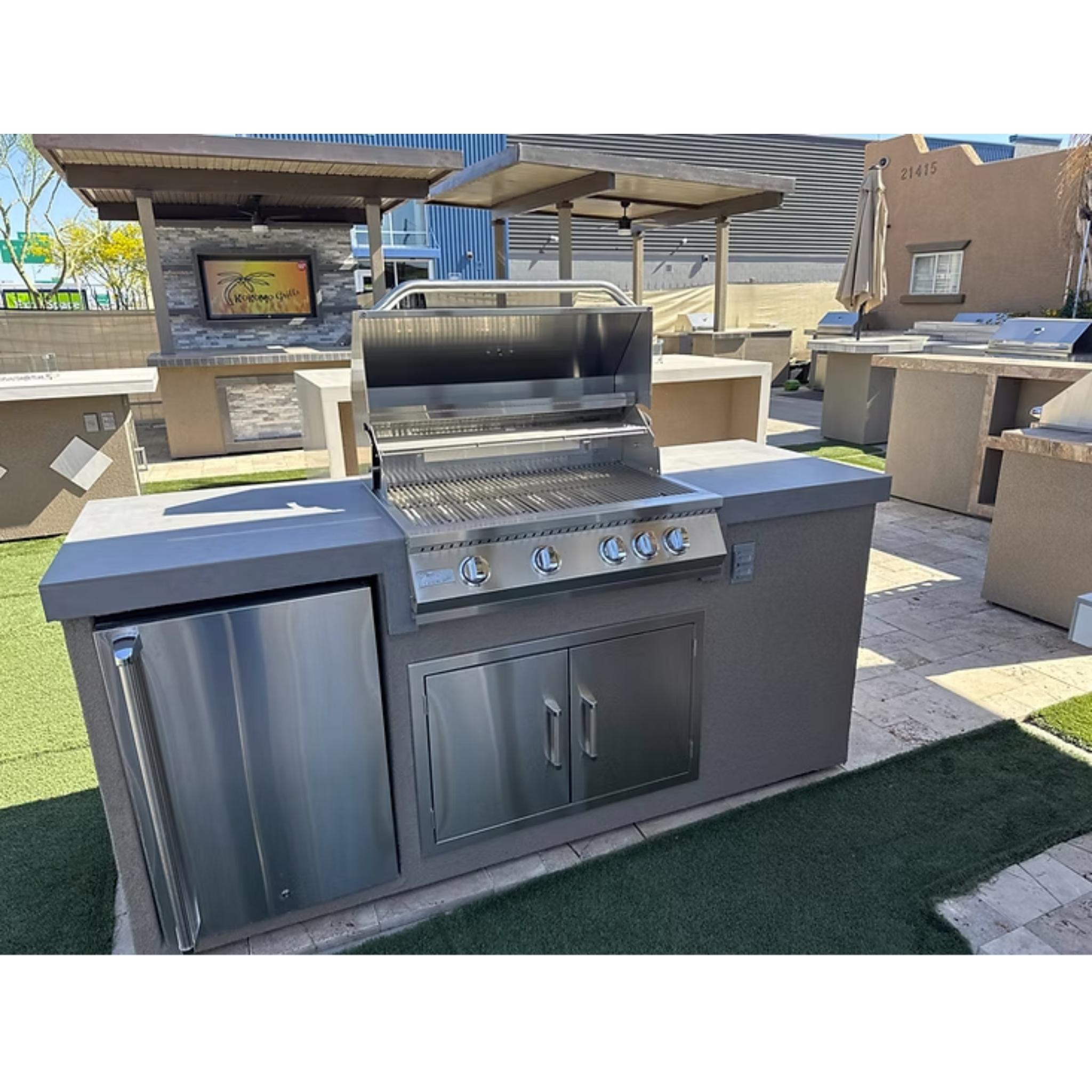 Outdoor kitchen grill with refrigerator and cabinets in a backyard setting