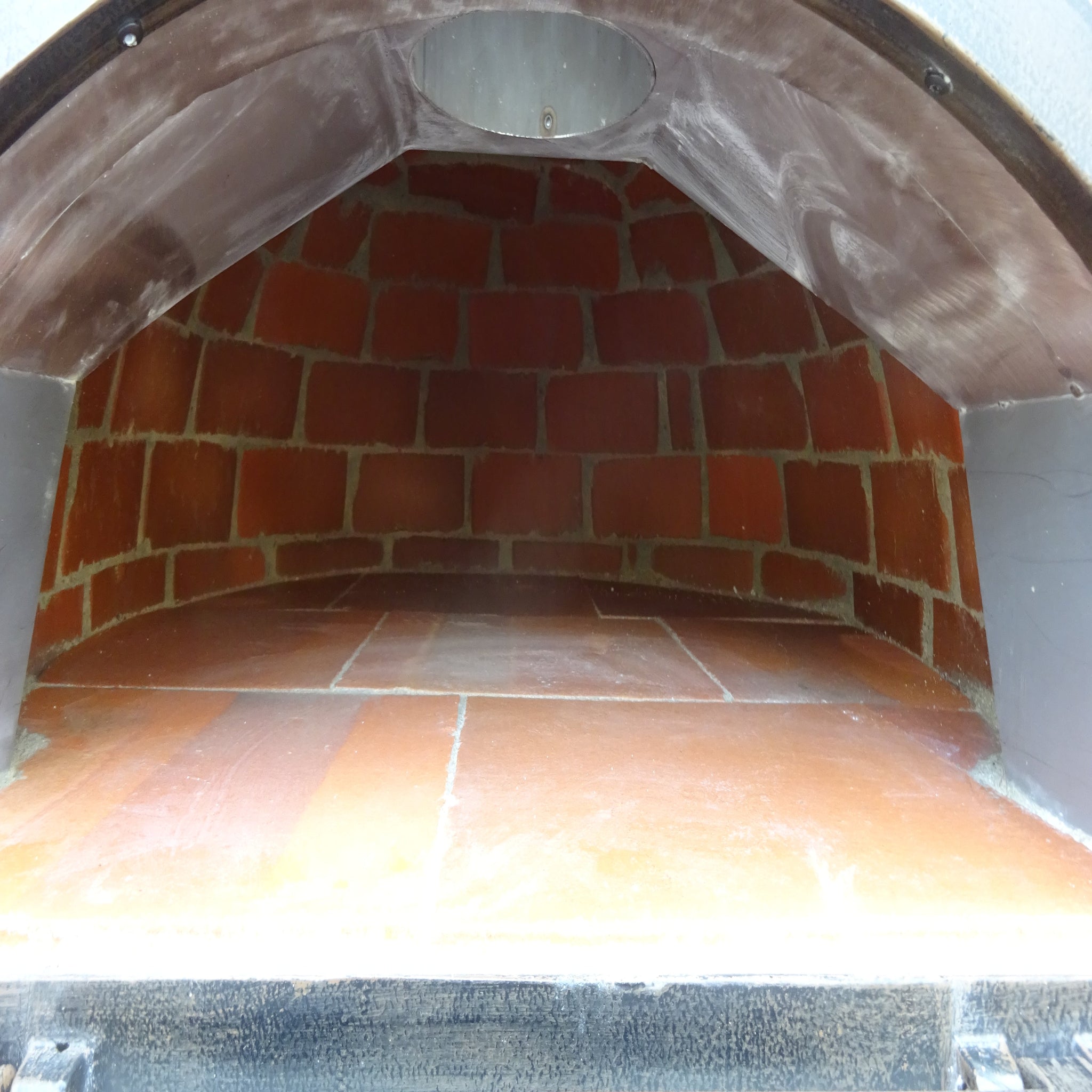 Brick oven with a metal door, showing the interior.
