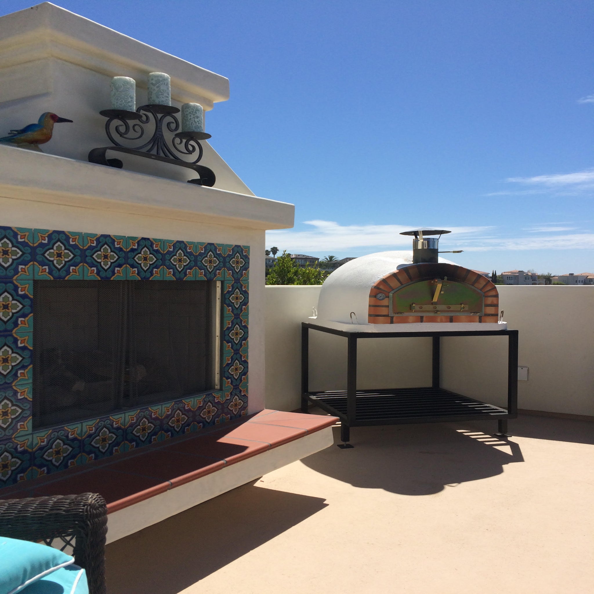 Outdoor rooftop setting with a pizza oven and tiled wall.