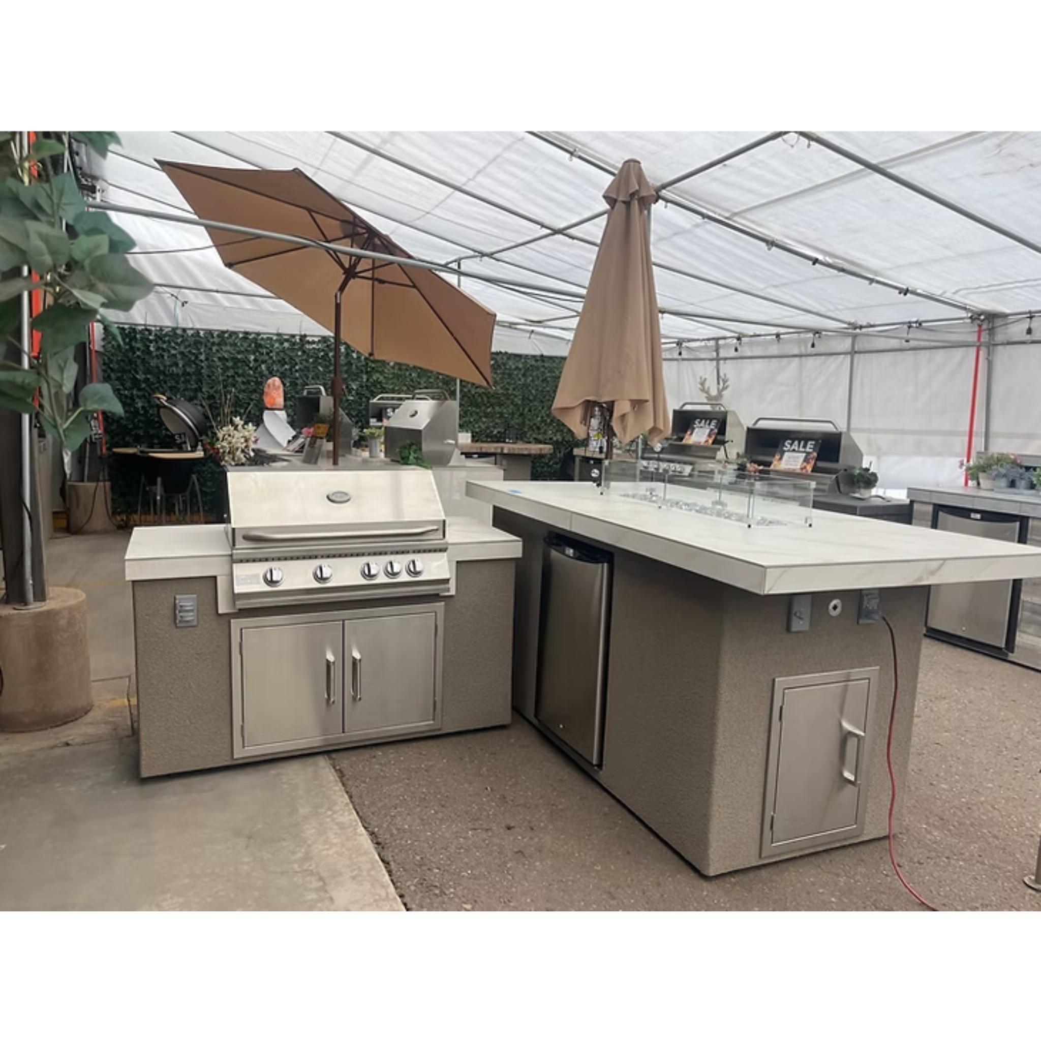 Outdoor kitchen setup with grill and refrigerator under a clear tent.